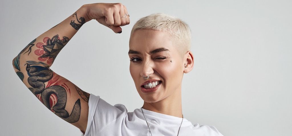 Les marques doivent oser l'audace Une jeune femme aux cheveux courts plie son biceps