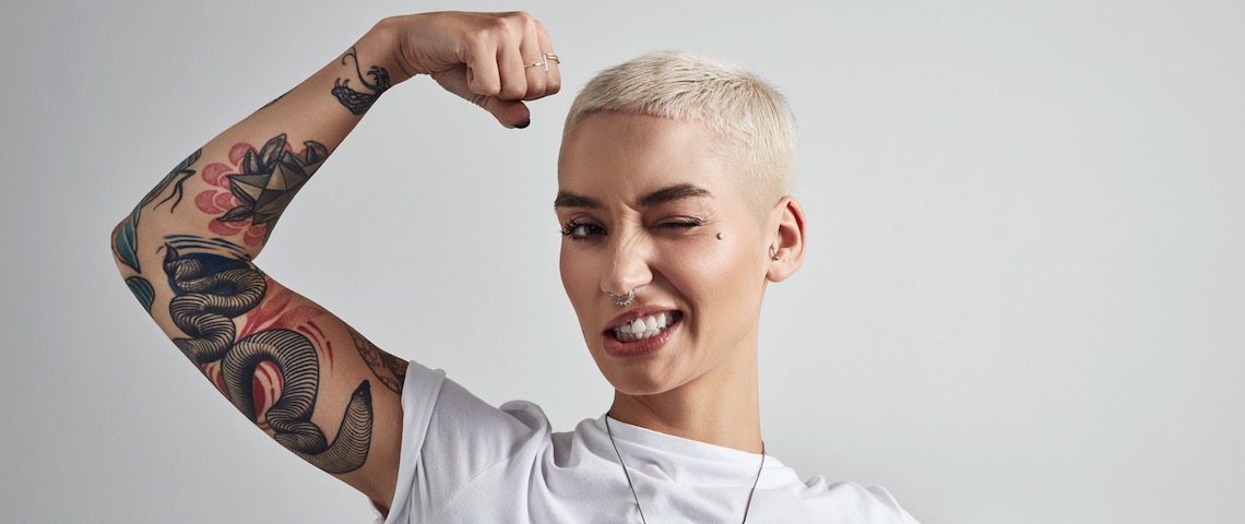 Les marques doivent oser l'audace Une jeune femme aux cheveux courts plie son biceps
