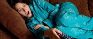 Une femme affalée sur son canapé en pyjama
