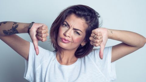 Une femme qui met les pouces vers le bas et qui fait la grimace.