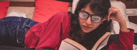 Quels livres lire pendant la crise ? Une femme indienne lisant un livre sur son lit