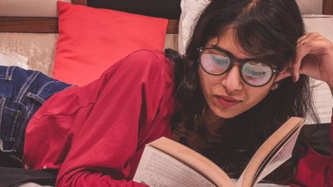 Une femme indienne lisant un livre sur son lit