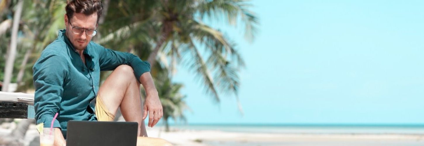 Les Nouveaux Nomades de Maxime Brousse Un homme qui regarde son ordinateur sur la plage
