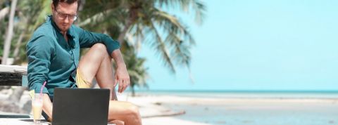 Les Nouveaux Nomades de Maxime Brousse Un homme qui regarde son ordinateur sur la plage