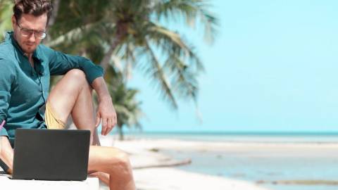 Un homme qui regarde son ordinateur sur la plage