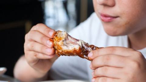 Un enfant qui mange une cuisse de poulet