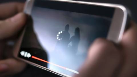 Une personne en train de lire une vidéo dont le téléchargement est lent sur son smartphone