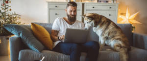 Un homme en train de travailler sur son canapé avec son chien