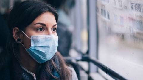 Comment ça se passe pour les gens qui sont obligés d'aller travailler pendant la pandémie ? Une femme dans un bus portant un masque chirurgical