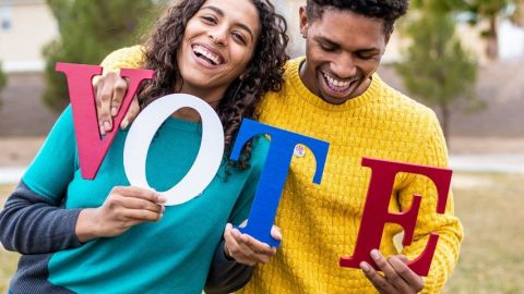 Un homme et une femme qui tienne des lettres qui forment le mot VOTE