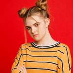 Une adolescente qui fait la tête devant un fond rouge