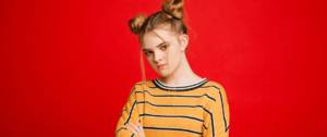 Une adolescente qui fait la tête devant un fond rouge