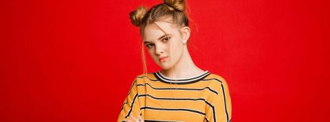 Comment la génération Z vit-elle la crise du Covid-19 ? Une adolescente qui fait la tête devant un fond rouge