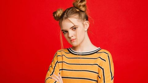 Une adolescente qui fait la tête devant un fond rouge