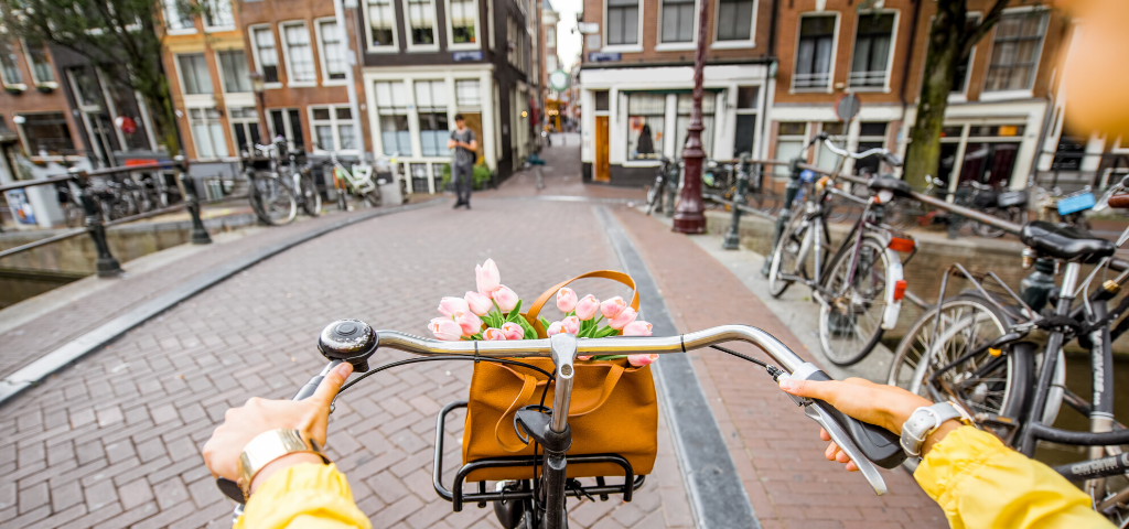amsterdam donut kate raworth jeune femme en pull jaune sur un vélo à Amsterdam