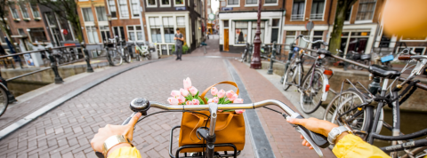 amsterdam donut kate raworth jeune femme en pull jaune sur un vélo à Amsterdam