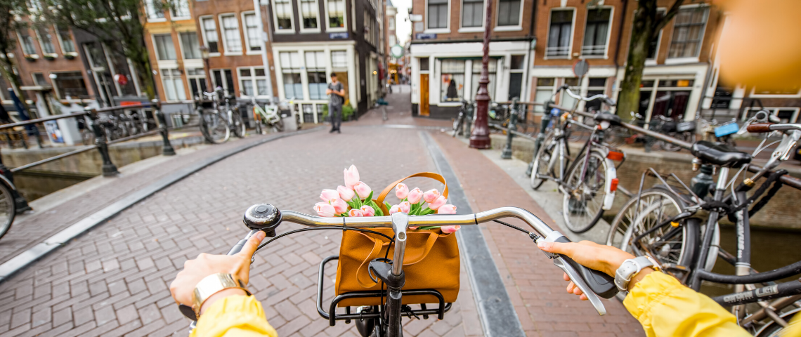 amsterdam donut kate raworth jeune femme en pull jaune sur un vélo à Amsterdam