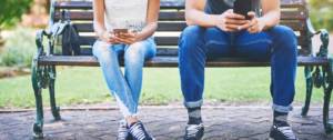 Deux personnes sur leur mobile sur un banc