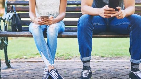 Deux personnes sur leur mobile sur un banc
