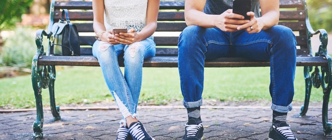 Deux personnes sur leur mobile sur un banc