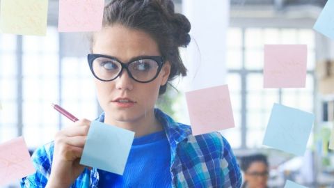Une femme qui écrit sur des post-it sur une vitre