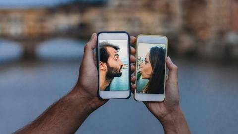 Deux visages sur des smartphones qui s'embrassent