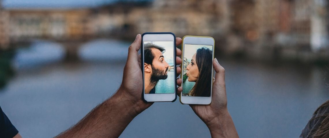 Le vocabulaire du dating spécial confinement Deux visages sur des smartphones qui s'embrassent