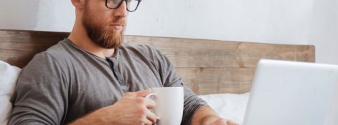 Les Français ont peur pour leur emploi pendant la crise Un homme dans son lit en train de boire un café et d'utiliser son ordinateur