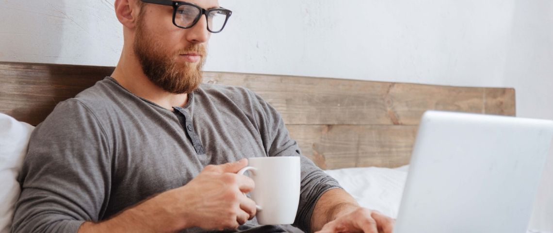 Les Français ont peur pour leur emploi pendant la crise Un homme dans son lit en train de boire un café et d'utiliser son ordinateur
