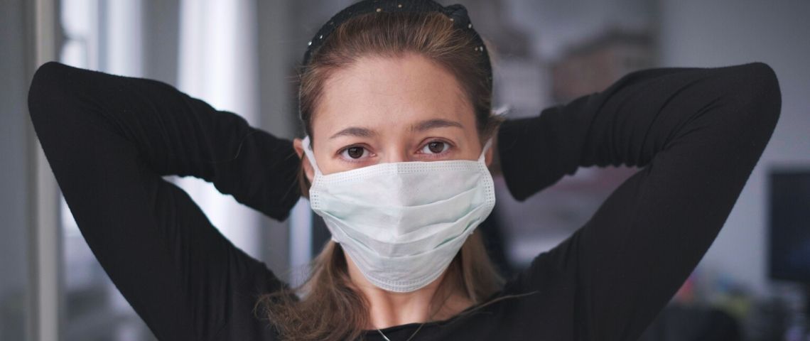 Les chiffres de la 5e semaine de confinement Une femme habillée en noir qui attache un masque chirurgical
