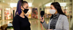 Une journaliste en train d'interviewer un femme portant un masque