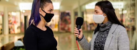 Une journaliste en train d'interviewer un femme portant un masque