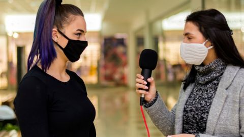 Une journaliste en train d'interviewer un femme portant un masque
