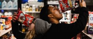 Une femme et un homme qui mangent des chips dans un supermarché
