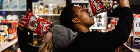 Comment le confinement modifie nos habitudes alimentaires Une femme et un homme qui mangent des chips dans un supermarché