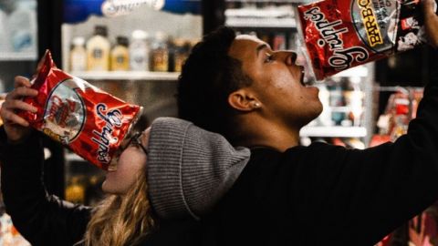 Une femme et un homme qui mangent des chips dans un supermarché