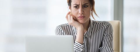 Comment bien rédiger ses mails pros pendant la pandémie Une femme qui regarde son écran d'ordinateur avec dégoût et surprise