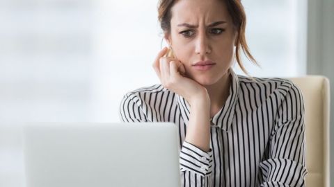 Une femme qui regarde son écran d'ordinateur avec dégoût et surprise