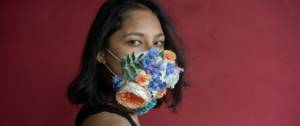 Une femme avec un masque à fleurs sur un fond rouge