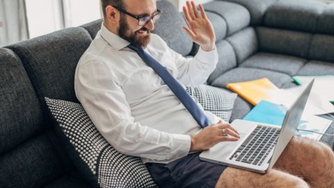 Un homme en caleçon, chemise et cravate en visioconférence dans son salon