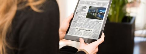 The Atlantic gagne des abonnés pendant la crise Une femme de dos qui lit le journal sur une tablette