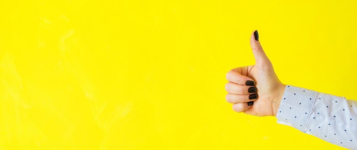 Trois startup utiles pendant le coronavirus pouce en l'air d'une femme sur fond jaune