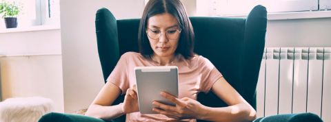 Comment la tech peut nous aider à lutter contre le stress en confinement ? Une femme asiatique tenant une tablette dans un fauteuil vert