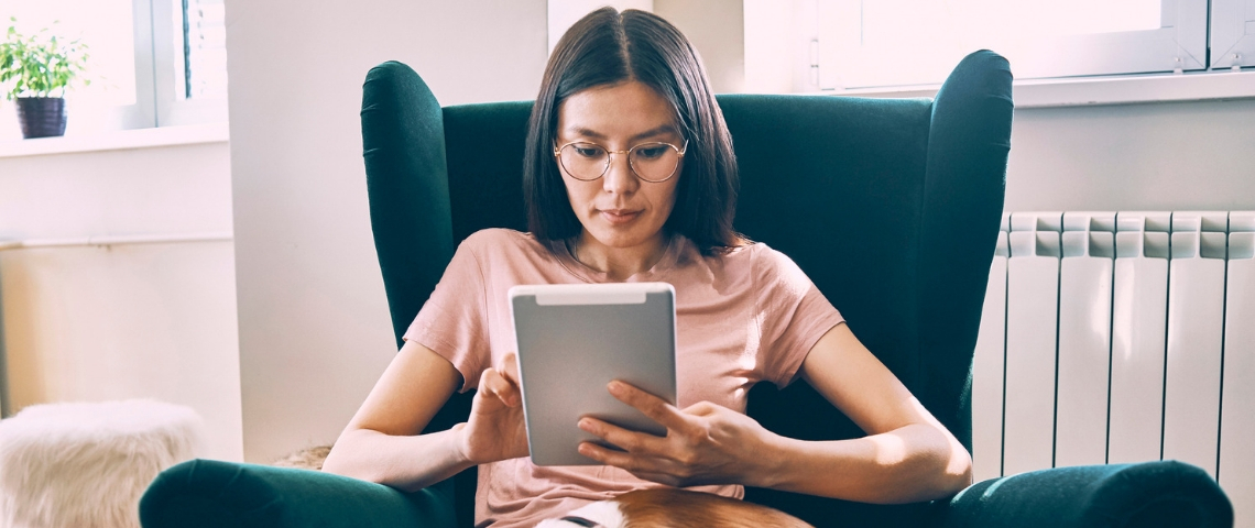 Comment la tech peut nous aider à lutter contre le stress en confinement ? Une femme asiatique tenant une tablette dans un fauteuil vert