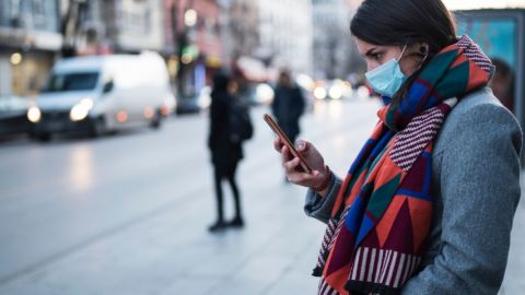 Une femme portant un masque en train d'utiliser son portable