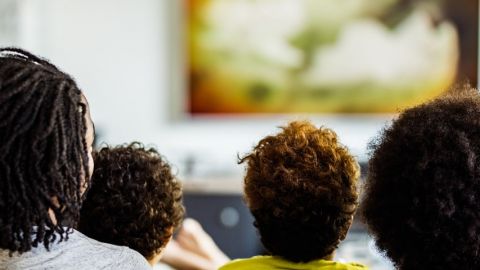Une famille de 4 personnes de dos en train de regarder la télévision
