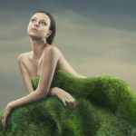 Une femme nue derrière une butte d'herbe
