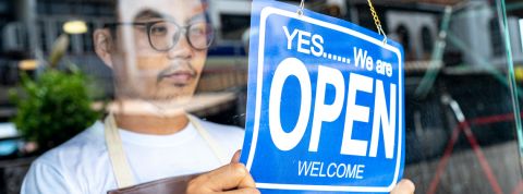 Déconfinement : comment les entreprises préparent leur retour Un jeune homme portant des lunettes et un tablier ouvre sa boutique