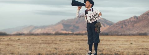 Qui sont ces gens qui diffusent des fake news ? Un enfant avec un mégaphone et un journal où il est écrit Fake News