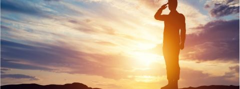 Comment les entreprises peuvent-elles s'inspirer de l'armée ? Un officier faisant un salut sur un fond de soleil couchant